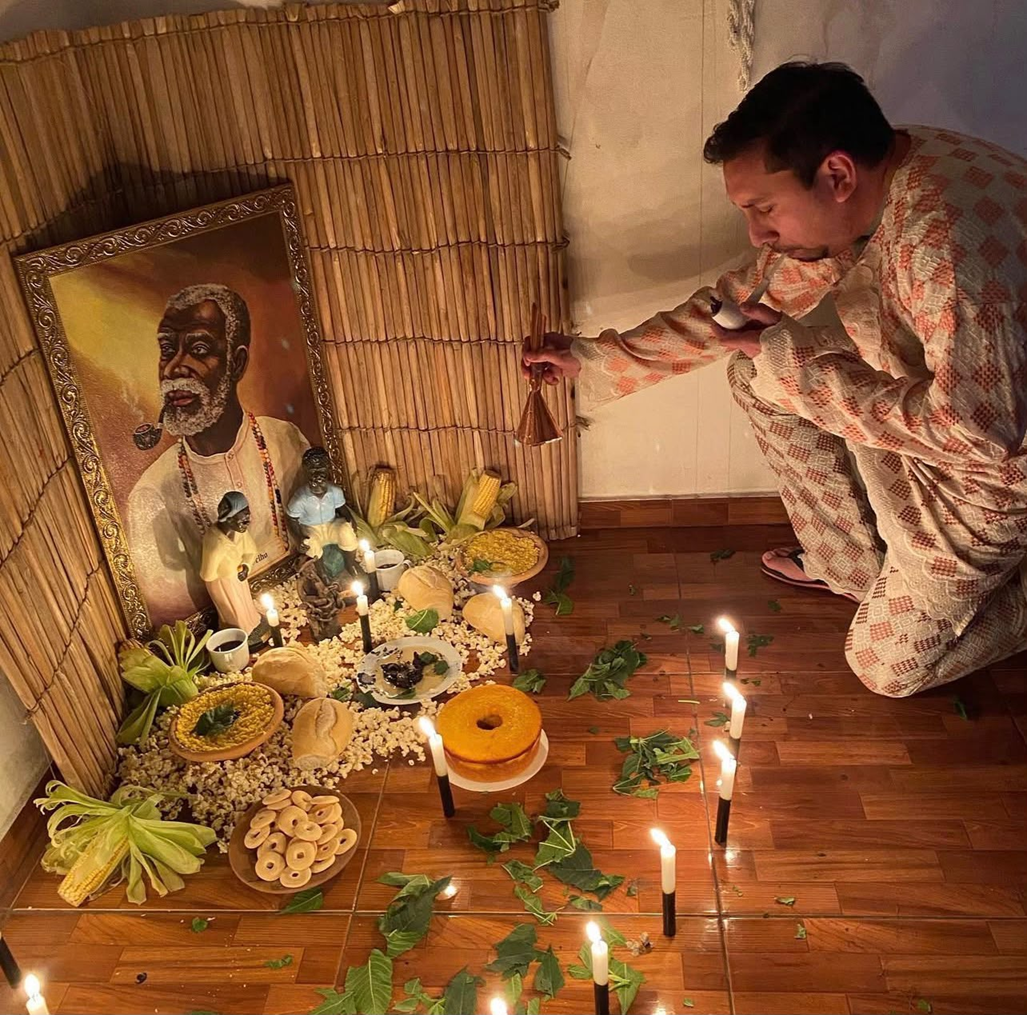 Pai Vinicius de Ogum realizando ritual espiritual com velas e oferendas